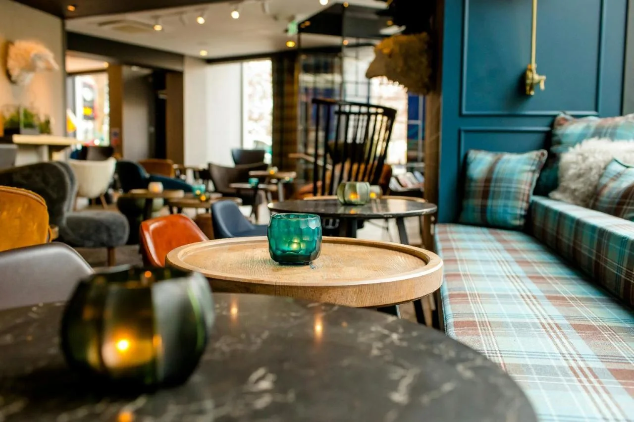 a restaurant with tables and chairs and a couch at Motel One Edinburgh-Royal in Edinburgh